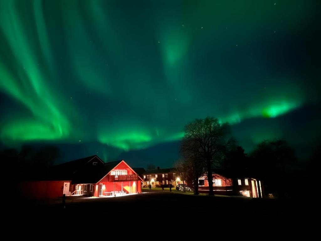 an aurora over a red house and a red barn at Kulturgården Bjerkem in Steinkjer