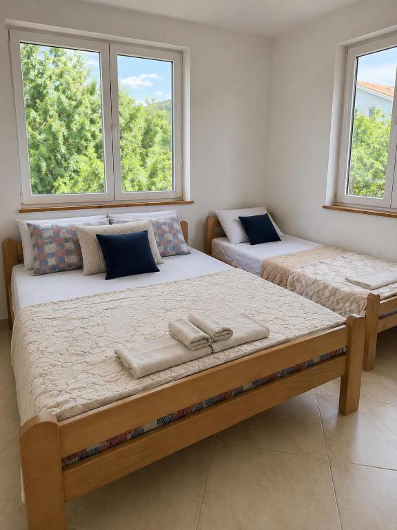 two beds in a room with two windows at Anit Rooms in Luštica