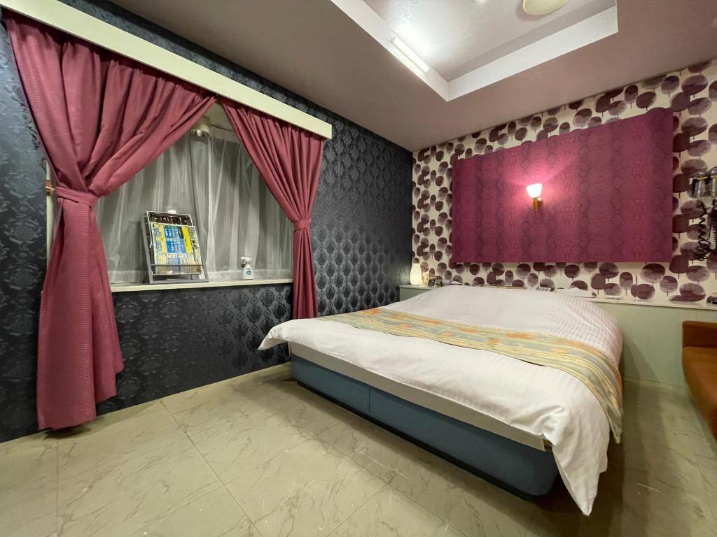 a bedroom with a bed with a purple curtain at ホテルレイクイン in Ono