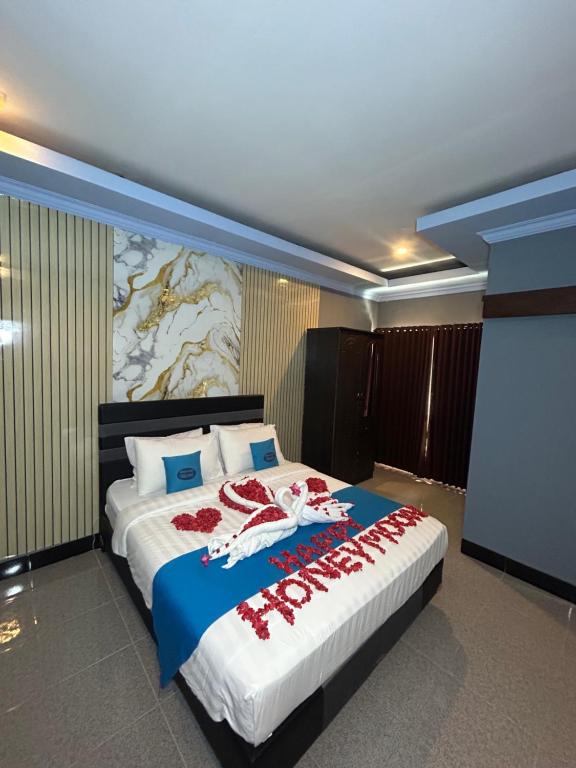 a bedroom with a large bed with a painting on the wall at Ridho Malik Hotel in Bumbang