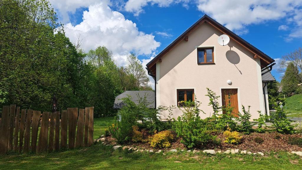 a small white house with a wooden fence at Chalupa Petra in Dolní Morava