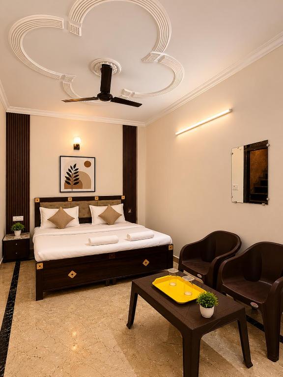 a bedroom with a bed and two chairs and a table at Wama Rooms in New Delhi