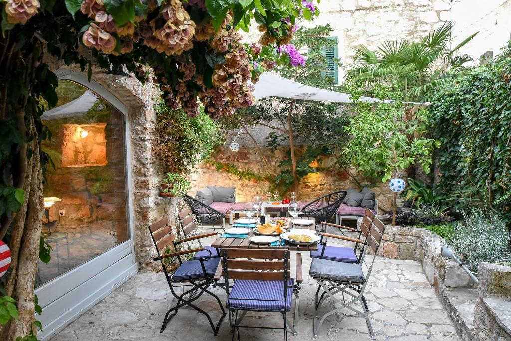 a patio with a table and chairs in a garden at Charming Stone House with Green Courtyard in Stari Grad