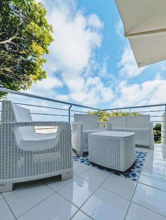 a patio with white wicker furniture on a balcony at Minnelea Blue Retreat in Acciaroli