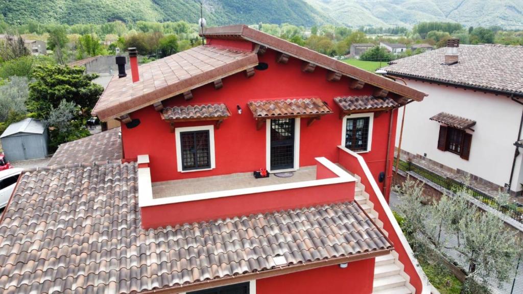 a red and white house with mountains in the background at Appartamento Villa Reale in Castel SantʼAngelo