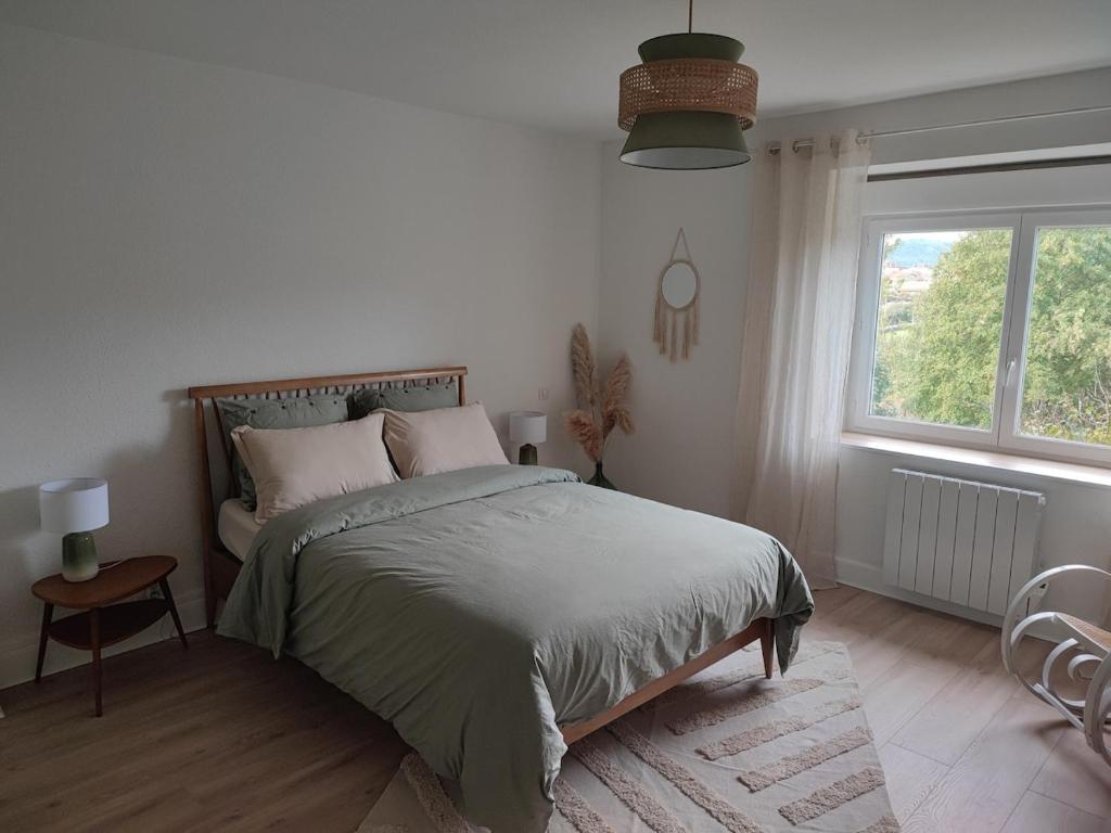 a white bedroom with a bed and a window at Logement cosy proche Cluny in Buffières