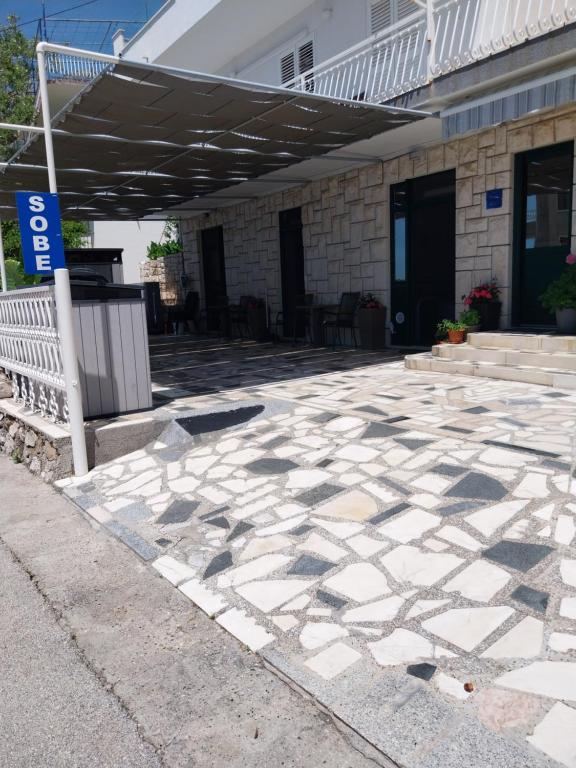 a stone patio with a bench and a building at Sobe Kraft 2 in Živogošće
