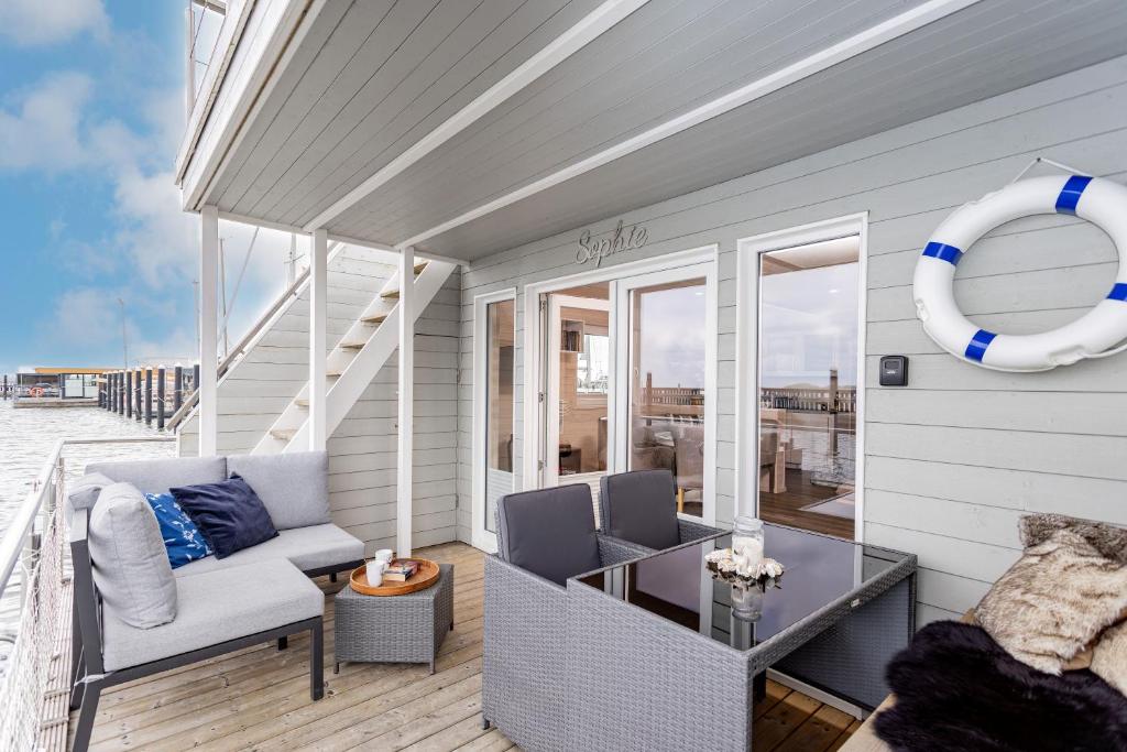 a patio with a couch and a table on a deck at Hausboot Sophie in Stralsund in Stralsund