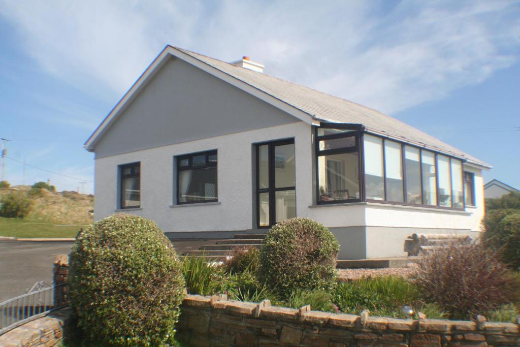 a small white house with windows on a street at Hillcrest Holiday Home in Cruit