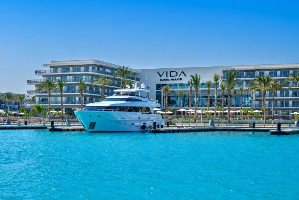 a yacht docked at a dock in front of a hotel at Apartment at Vida Marina Marassi, North Coast in El Alamein