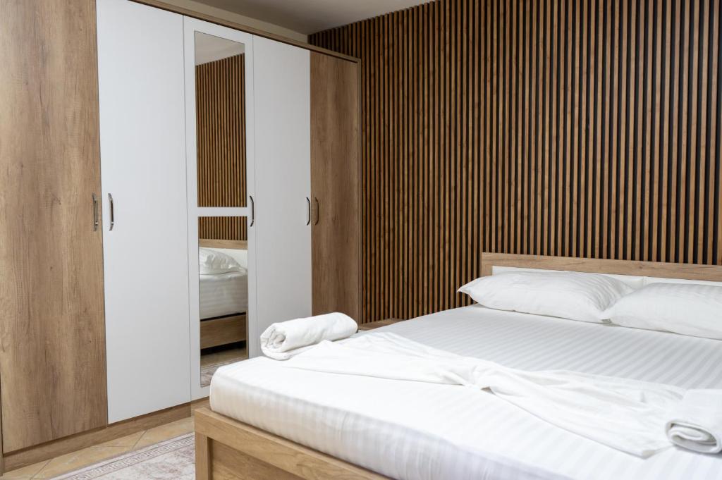 a bedroom with a white bed and a wooden wall at Mandi Apartament in Tirana