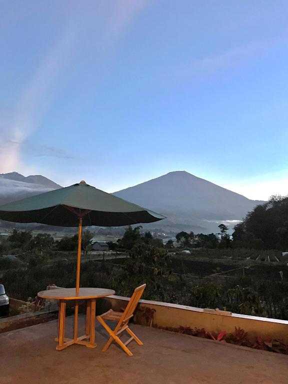 a table and chairs with an umbrella on a roof at Sun Grace Villa and Camp in Sembalun Lawang