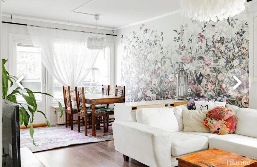 a living room with a white couch and floral wallpaper at Tina's Apartment in Pori