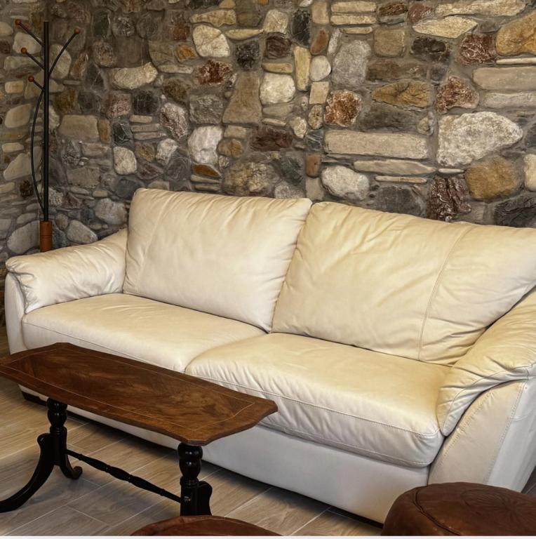 a white couch in a room with a stone wall at Villa Katerinaki in Kos