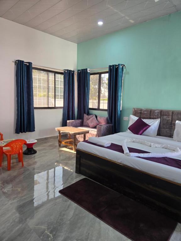 a bedroom with a large bed and a couch at Rainbow Cottage Stays in Kānha
