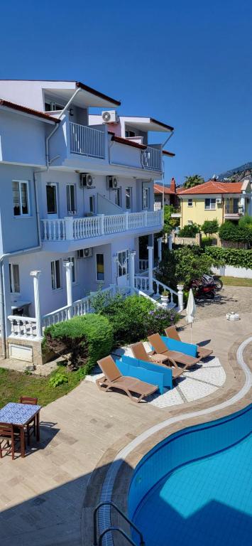 a large white house with a swimming pool and chairs at mavikösk apartement in Dalyan
