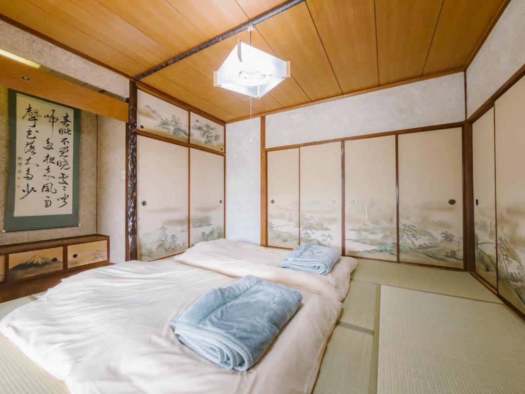 a bedroom with a bed with two blue pillows on it at 温泉街近くの一棟貸し ひだまり in Kirishima