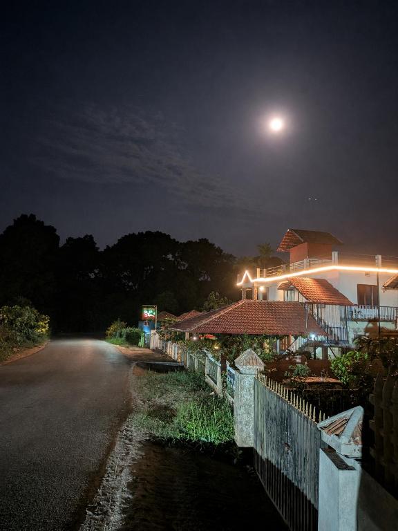 a house with a fence next to a street at night at Coorg Relax Home in Madikeri