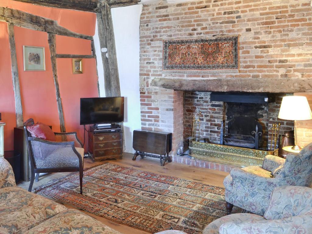 a living room with a fireplace and a tv at Red Lion Corner in Lavenham