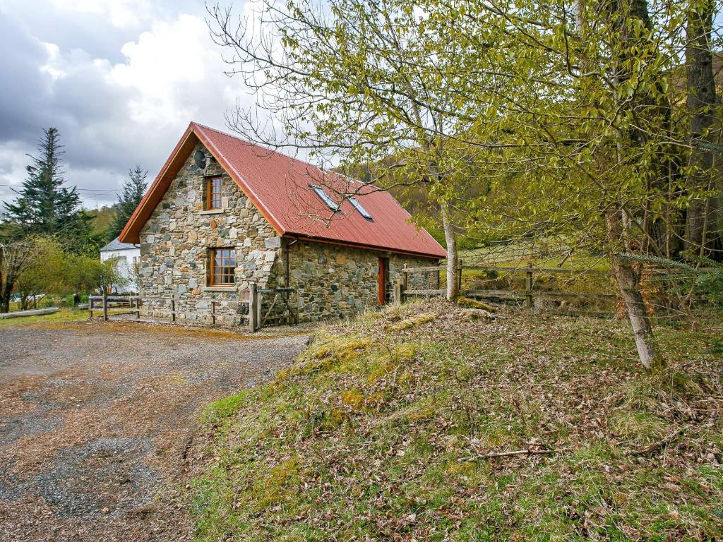 a stone barn with a red roof on a road at The Barn - S4593 in Lochearnhead