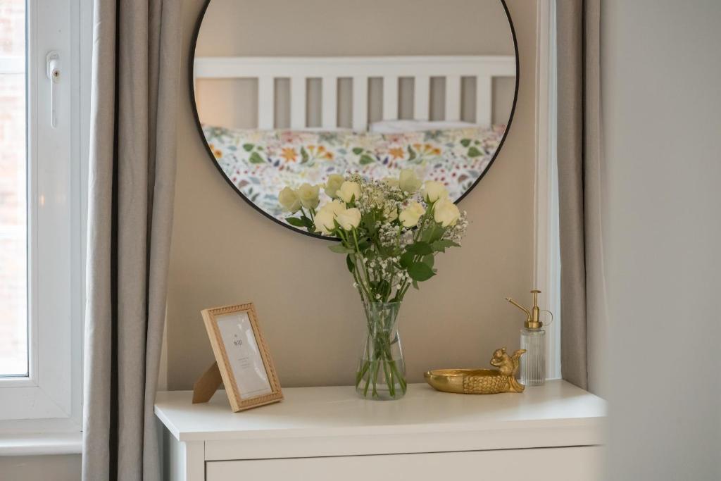 a vase of flowers on a dresser under a mirror at Castleview in Hillsborough