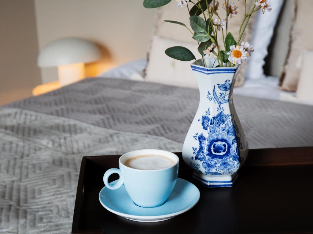 a cup of coffee and a vase with flowers on a table at Tip !!! Appartementen Leonardus in Valkenburg