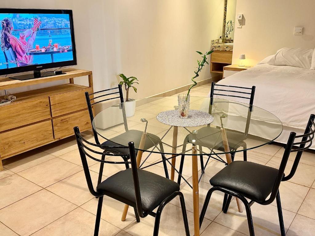 a dining room with a glass table and chairs and a television at Verde Limon Loft (monoambiente) in San Salvador de Jujuy