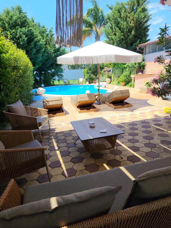 a patio with chairs and a table and an umbrella at Luxury Villas Chrysa Private Pool & Spa in Nafplio