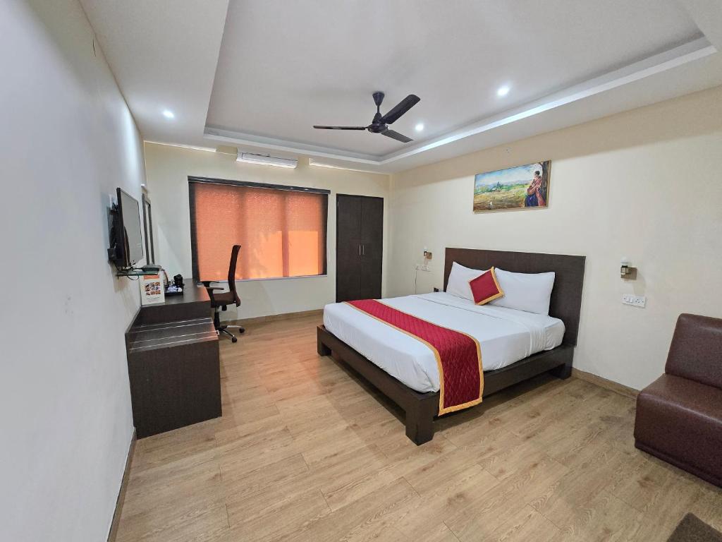 a bedroom with a bed and a desk and a chair at Hotel Ashok Residency, Porur in Chennai