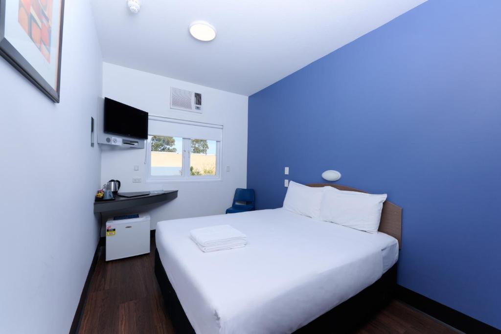 a bedroom with a white bed and a sink at ibis Budget Perth Airport in Perth