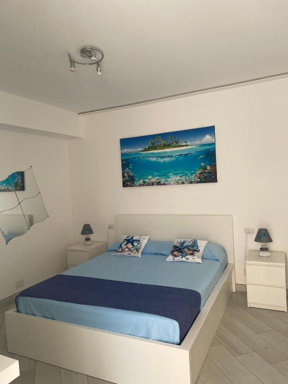 a white bedroom with a bed with blue sheets at SoleMare Rooms "Acquamarina" in Procida