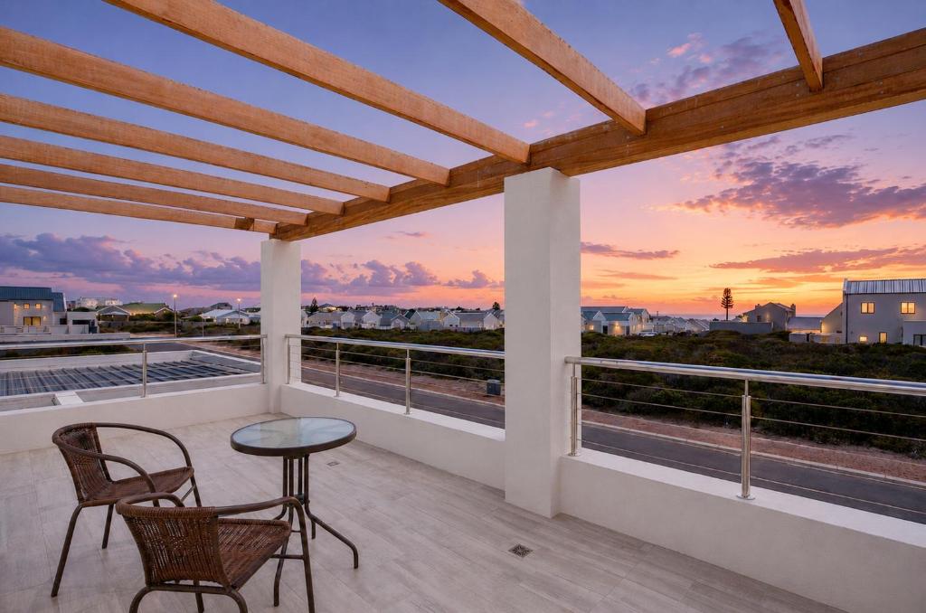 a balcony with a table and chairs and a sunset at Yzer4You in Yzerfontein