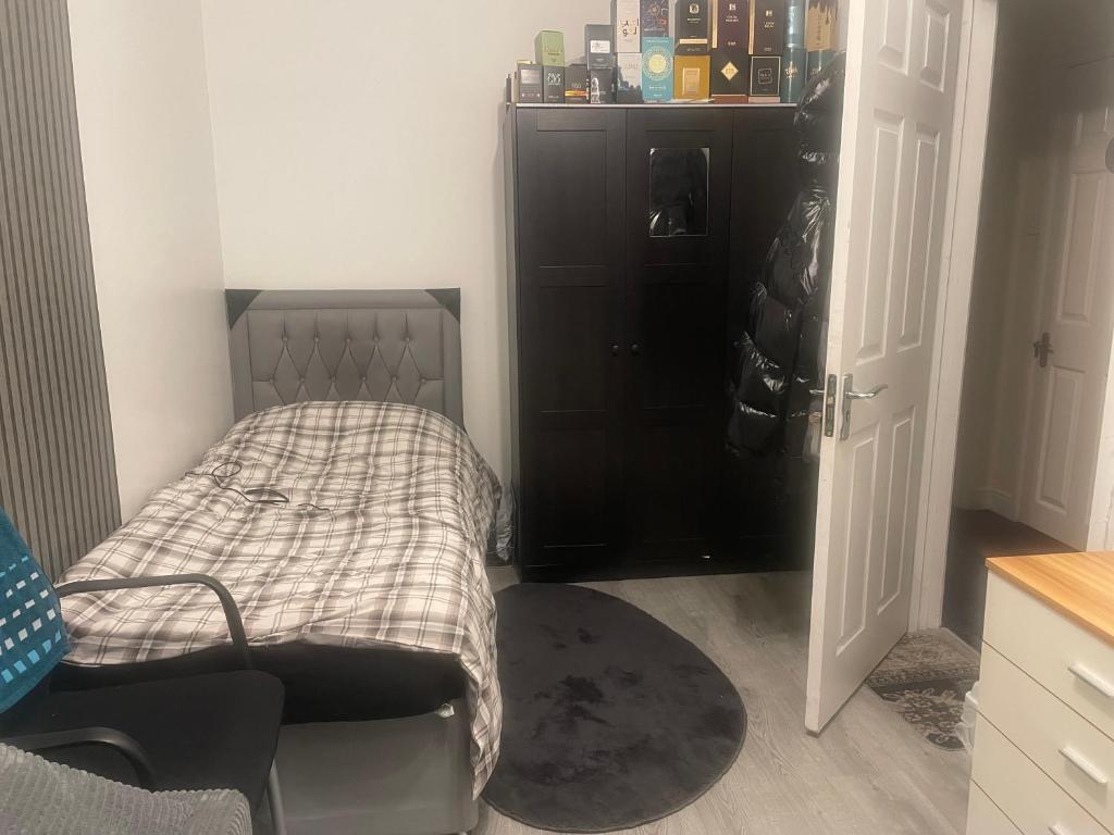 a small bedroom with a bed and a black cabinet at Room Younis in Tilehurst