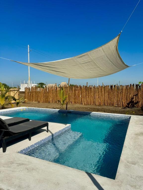 a swimming pool with a canopy over a wooden fence at Secret Garden Cottage in El Naranjo
