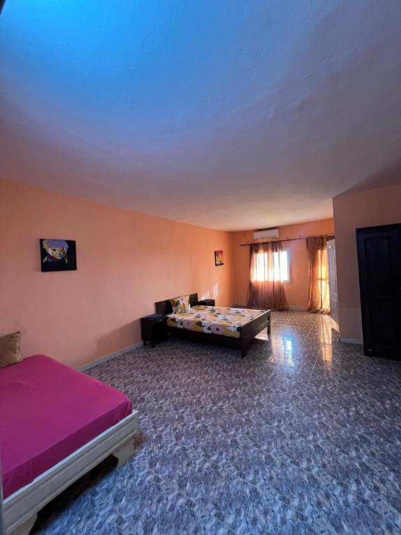 ein Zimmer mit einem Bett und einem Tisch darin in der Unterkunft Chalet rose in Toubab Dialao