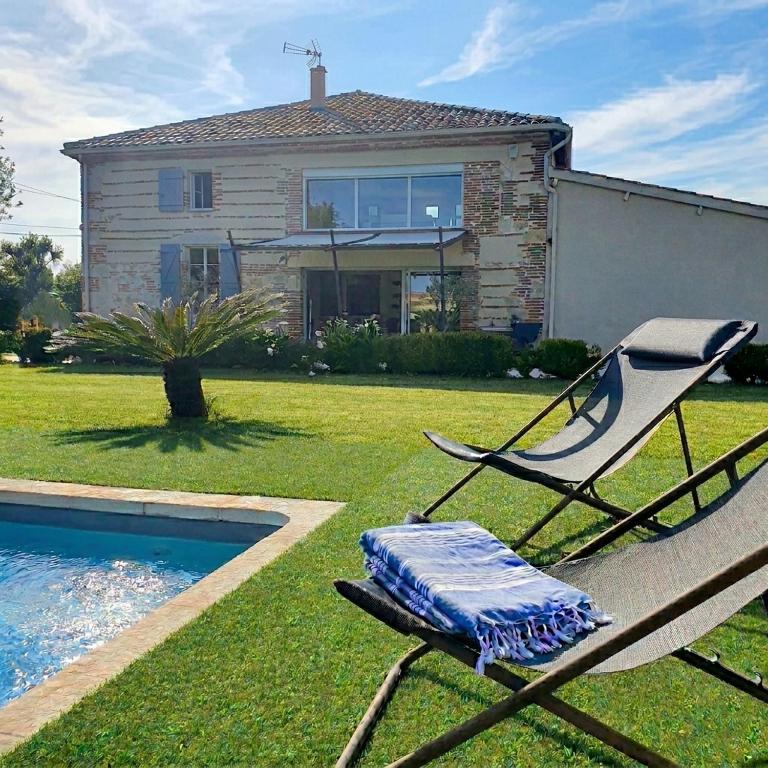 a chair sitting in the grass in front of a house at L'OUSTAL D'ADELE proche Canal du Midi et Moissac in Saint-Nicolas-de-la-Grave