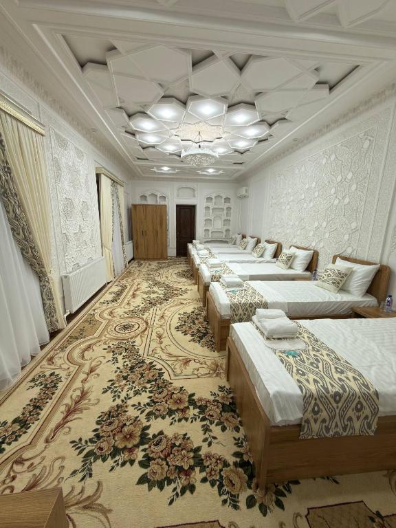 a row of beds in a large room with a rug at Silk Road Hostel in Bukhara