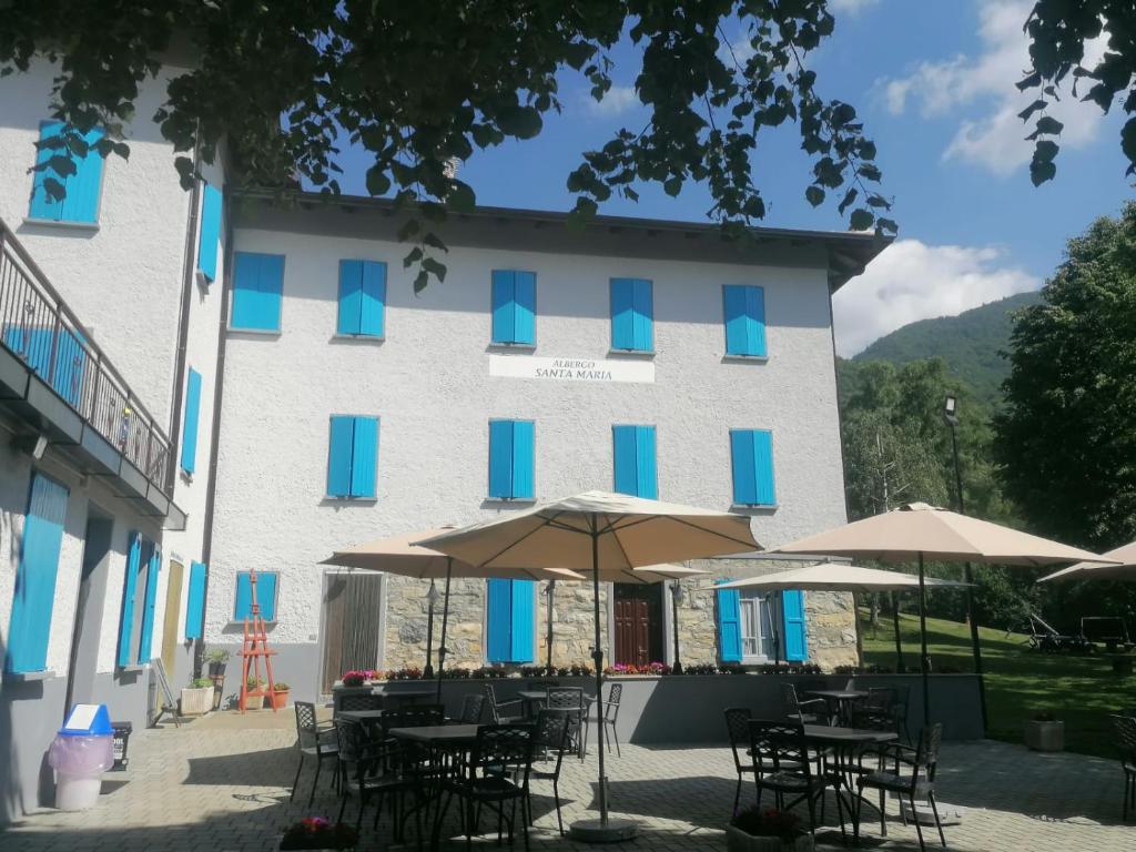 a building with tables and umbrellas in front of it at Albergo Santa Maria in Esino Lario
