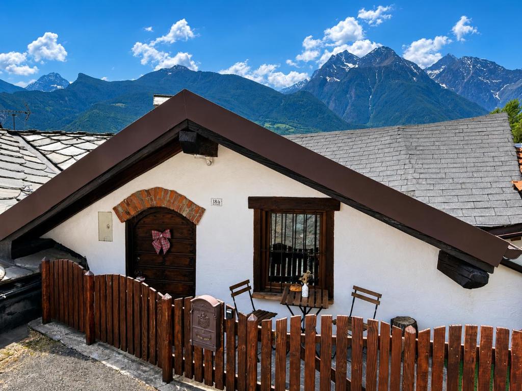 a house with a fence and mountains in the background at Belle vue des Alpes in Blavy