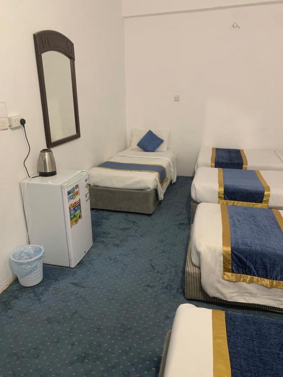 a hotel room with three beds and a mirror at Nour Taba Apartments in Medina