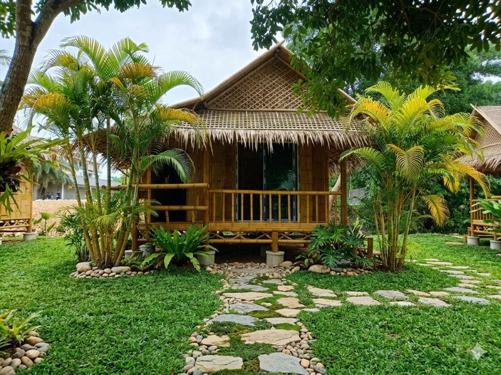 a house with a deck in front of a yard at Long Beach Bamboo House in Ban Ai Dao