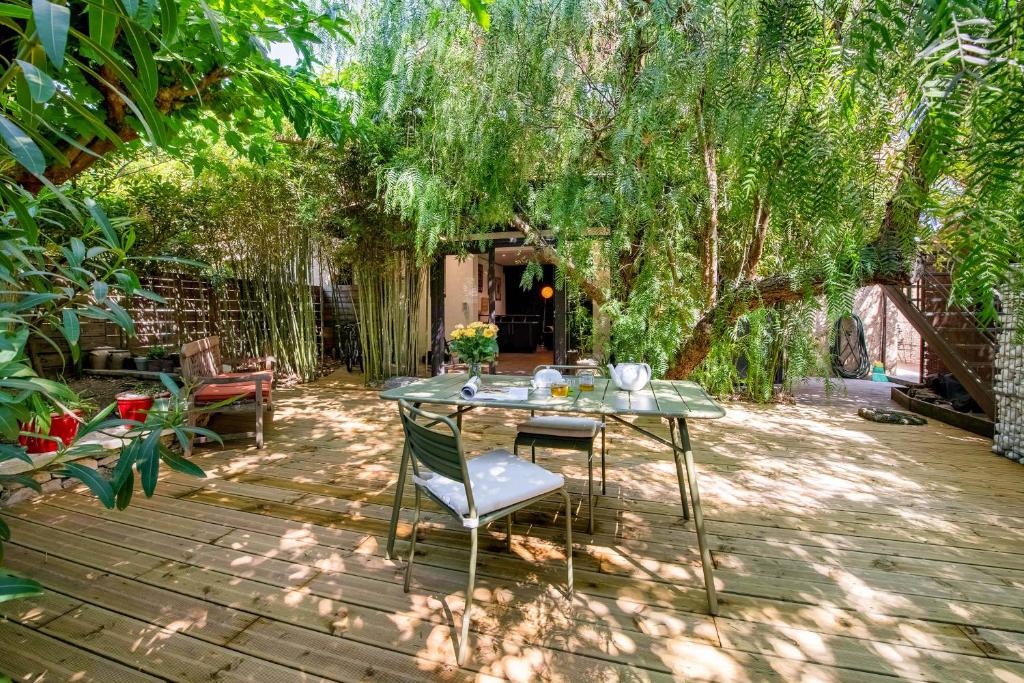 a patio with a table and chairs under a tree at les Aromatiques - terrasse & parking privé à VILLENEUVE LES AVIGNON - proche Golf Academy in Villeneuve-lès-Avignon