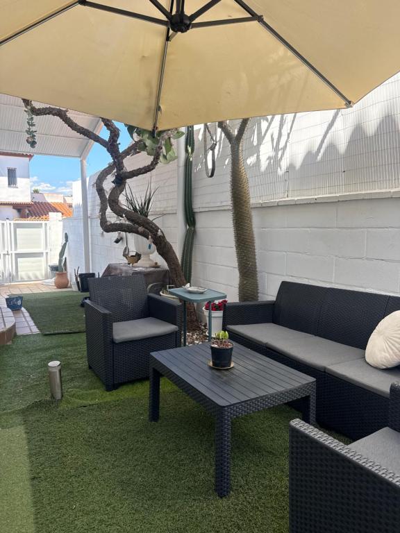 a patio with couches and a table and an umbrella at New Garden in Mairena del Aljarafe