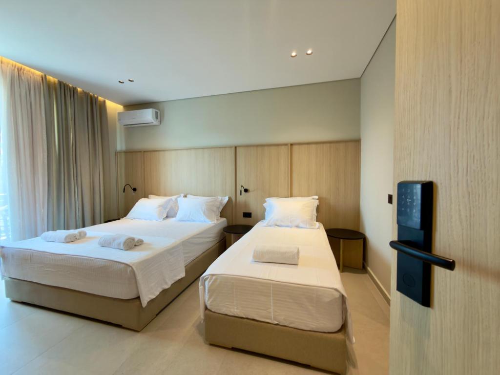 a hotel room with two beds and a tv at RAI Rooms Saranda in Sarandë