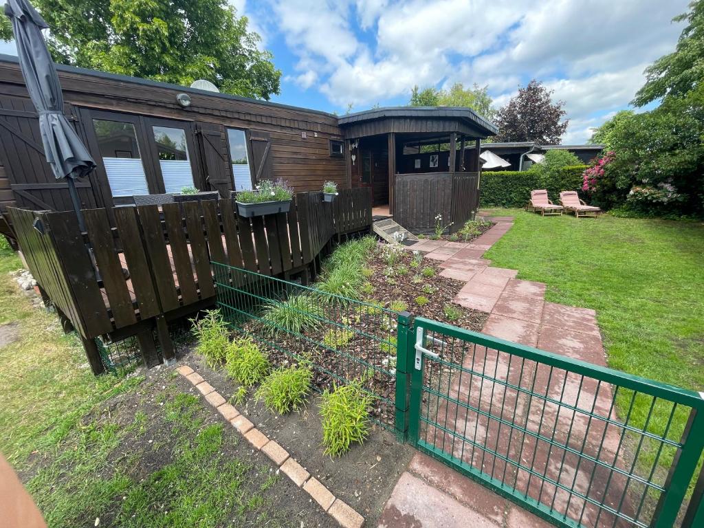 a tiny house with a fence and a yard at Marla zum Strand in Garrel