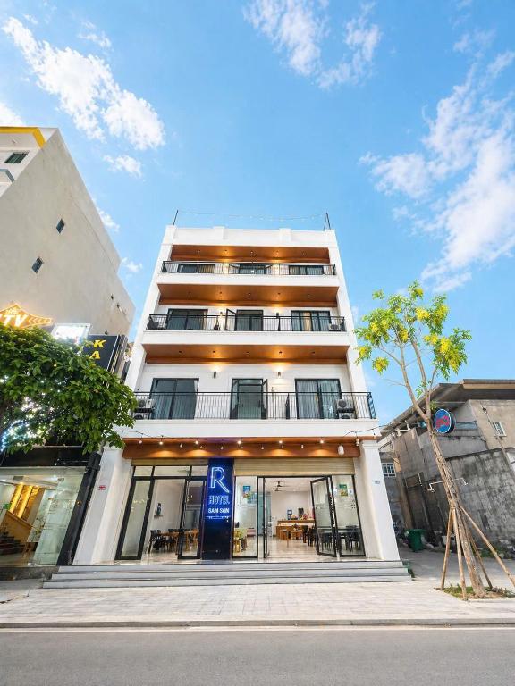 a tall white building with a blue sign on it at R Hotell in Sầm Sơn