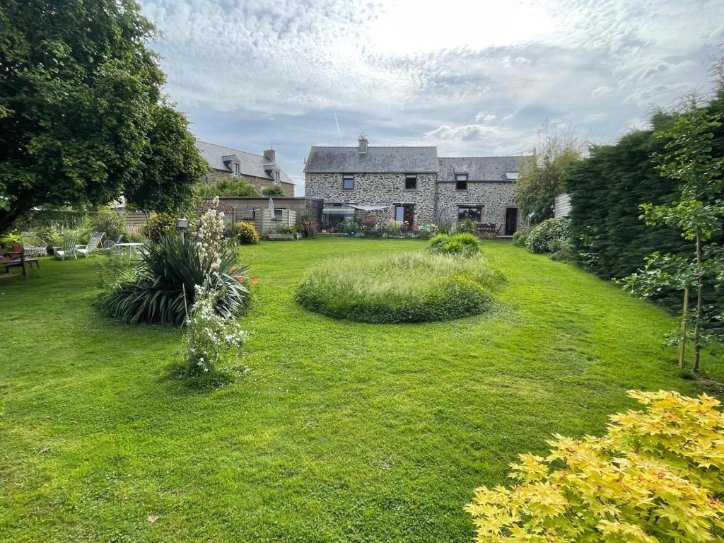 a large yard with a house and a grass field at Chambres d'hôtes vive l'instant à Saint-Hélen in Saint-Hélen
