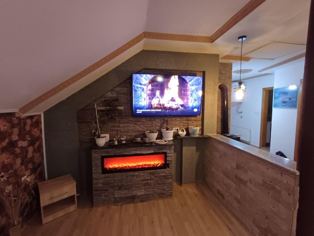 a living room with a fireplace with a tv above it at Apartman Denis Una in Lužine