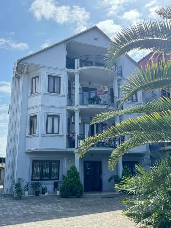 a white building with a palm tree in front of it at Hotel Kobuleti Garden in Kobuleti