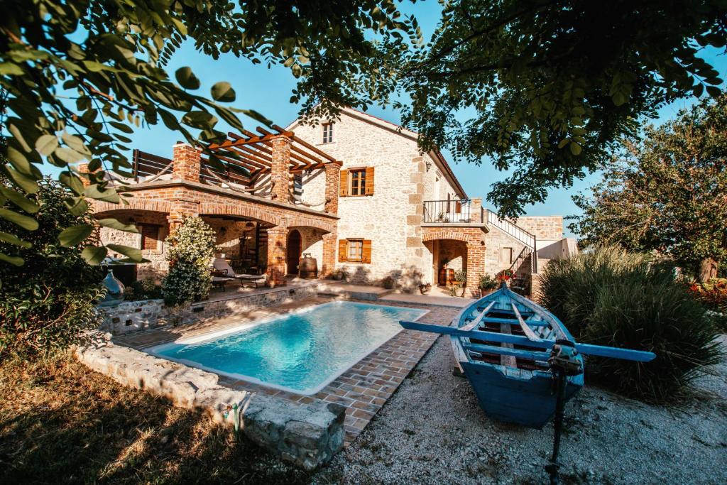 a house with a swimming pool and a boat in front of it at Villa Romantika Dalmacija in Nin